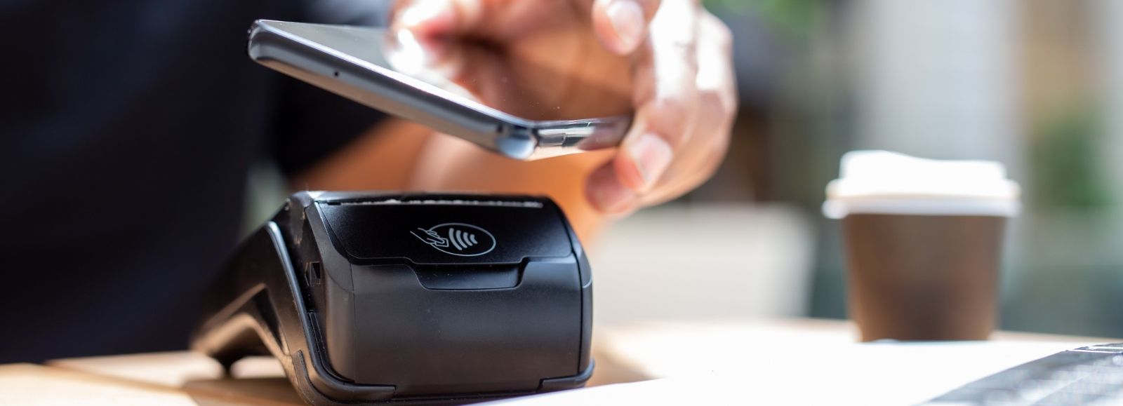 Image of phone using digital wallet tap a credit card machine.